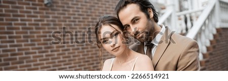 young groom in beige suit and pretty bride looking at camera, banner