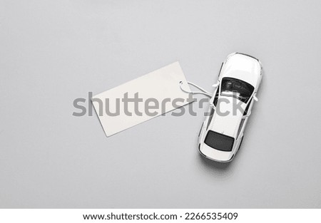 Toy car model with price tag on a gray background. Top view