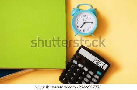 The word PRICE written on a calculator and a yellow background. Along with folders and an alarm clock. Finance or business concept.