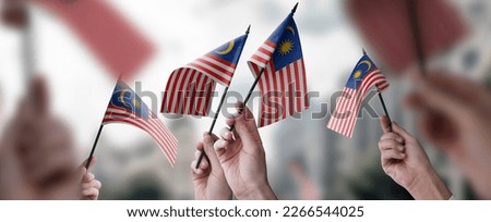 A group of people holding small flags of the Malaysia in their hands. Royalty-Free Stock Photo #2266544025