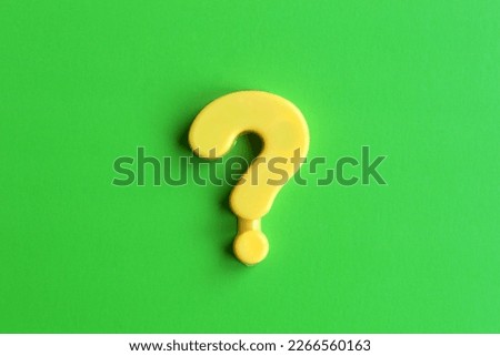 A yellow question mark lies on a green background.