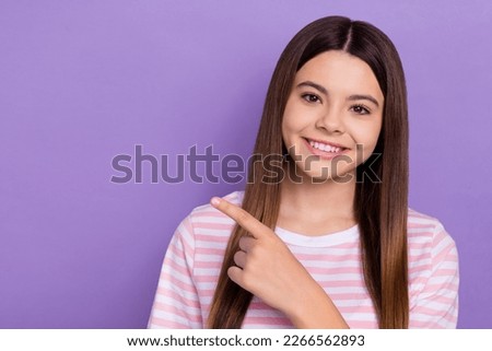 Photo of positive lovely girl toothy smile indicate finger empty space isolated on violet color background