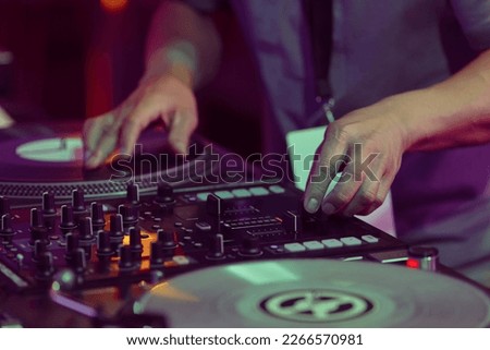 Hip hop DJ scratches vinyl records on turntables. Hands of disc jockey scratching record on turn table player in close up