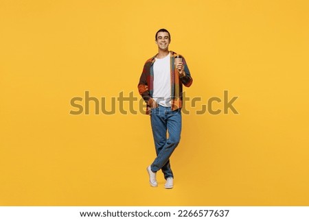 Full body young middle eastern man 20s he wear casual shirt white t-shirt hold takeaway delivery craft paper brown cup coffee to go isolated on plain yellow background studio People lifestyle concept Royalty-Free Stock Photo #2266577637