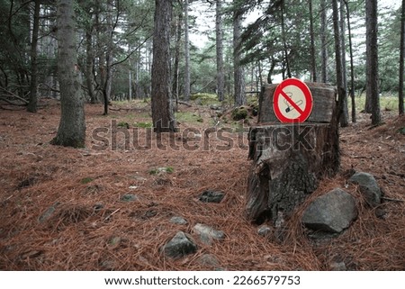 A no smoking sign has been placed on a trunk cut in the shape of a seat in the forest of the priory St Michel de Grandmont (St Privat, Hérault, Occitanie, France)