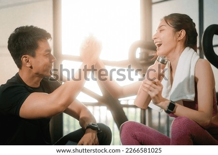Young slim fitness Asian woman sitting and shake hands with personal trainer conversation for a break in the gym. The athlete leads a healthy lifestyle. Cardio training for weight loss. Royalty-Free Stock Photo #2266581025