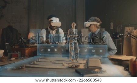 Two multi ethnic tailors in VR headsets in atelier. 3D female hologram of garment pattern. Virtual interface menu of program for designing and modeling clothes. Concept of AR modern technologies.