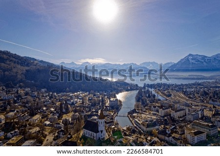 Aerial view of City of Thun with Aare River, Lake Thun an famous peaks Eiger, Monk and Virgin in the background on a sunny winter day. Photo taken February 21st, 2023, Thun, Switzerland.