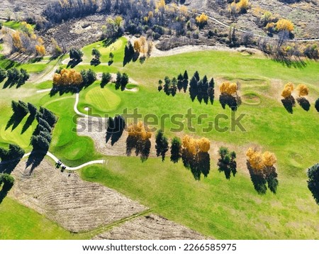 Drone aerial view of beautiful golf course field in Canada with autumn trees and fall colors. Top view of people playing golf in minimalist style. 