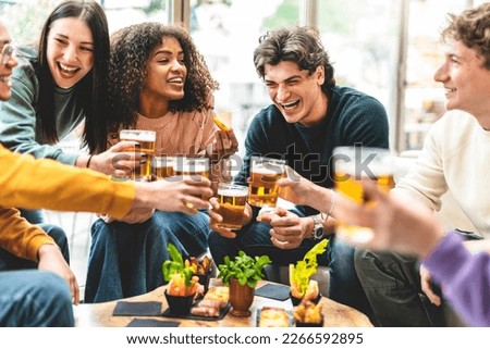 Multiracial friends drinking and toasting beer at brewery bar pub-Happy diverse people cheering glasses and having fun enjoying happy hour celebrating party-Beverage life style concept with guys Royalty-Free Stock Photo #2266592895