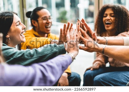 Multiracial happy young people stacking hands-Group of diverse friends having fun unity together indoors at table of community-Human resources Concept Creative and Relationship Youth Culture Royalty-Free Stock Photo #2266592897