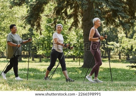 Side view portrait of senior women walking with poles in green park Royalty-Free Stock Photo #2266598991