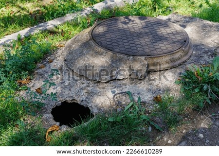Dangerous pit of failed asphalt near the sewer manhole. Background with selective focus and copy space for text