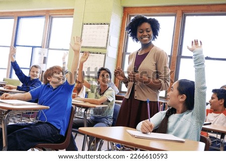 School, tutor and students raise their hands to ask or answer an academic question for learning. Diversity, education and primary school kids speaking to their woman teacher in the classroom. Royalty-Free Stock Photo #2266610593