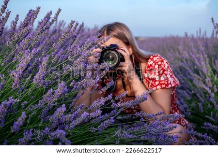 Beautiful woman taking pictures outdoors with a DSLR camera. Female professional photographer, taking photos in a lavender field.