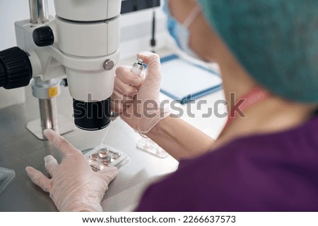 Embryologist examinesbiomaterial collected in embryo blocks under microscope Royalty-Free Stock Photo #2266637573