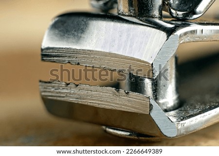 Closeup, focus stacked, macro shot of a chrome masculine dirty nail cutter on wood.