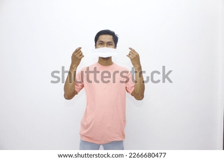 asian man in pink wearing white mask on white background. wearing a mask to prevent transmission of the virus.