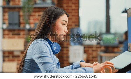 Asian woman working as editor with graphic tablet and stylus, using photo editing software to fix color grading for multimedia production. Creative artist developing media design. Close up.