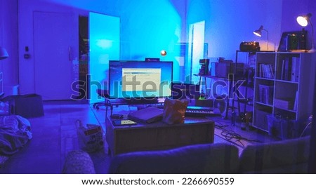 Programming room, information technology or tv in house for software, hacking or coding in neon light at night. It, television or living room interior with digital devices, sofa or piano with screen. Royalty-Free Stock Photo #2266690559
