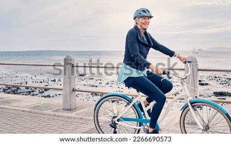 Happy, smile and cycling with old woman at beach for fitness, peace and travel with blue sky mockup. Relax, workout and retirement with senior lady riding on bike for nature, health and wellness