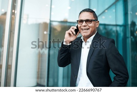 Ive just stepped out. Cropped shot of a handsome mature businessman making a phonecall with his office in the background.