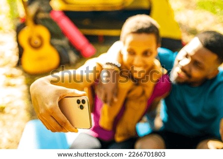 afro latin couple in tent taking selfie using modern smartphone