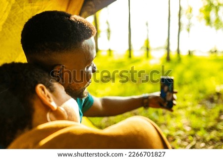 afro latin couple in tent taking selfie using modern smartphone