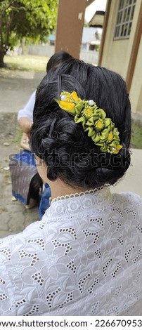 Asians Women's hair bun style with yellow and green flower ribbons. The style suitable to be applied at the at weddings or church events