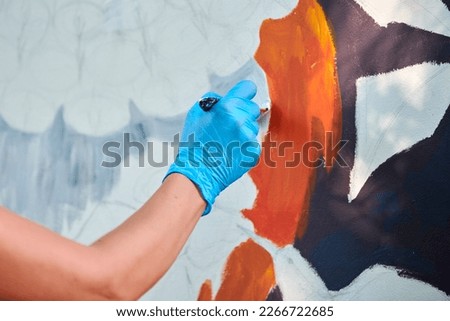 Woman artist hand holds paint brush and draws abstract surreal image on white canvas at outdoor art painting festival, paintings art picture process. Woman artist paints atmospheric surreal picture