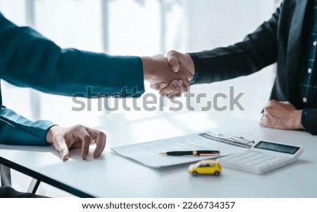 Shaking hands after succesful sign a contract and pay for money, A car dealer or sales manager offers to sell a car and explains the terms of signing a car and insurance contract.