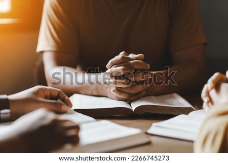 Christian group of people holding hands praying worship together to believe and Bible on a wooden table for devotional for prayer meeting concept. Royalty-Free Stock Photo #2266745273