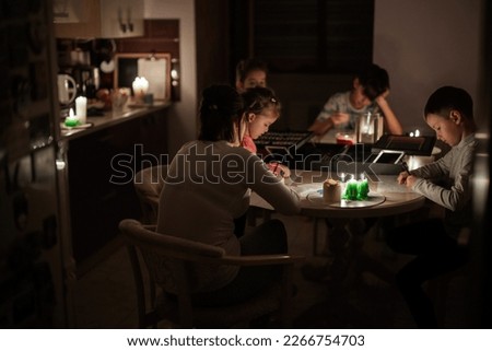 Family spending time together during an energy crisis in Europe causing blackouts. Kids drawing in blackout. Royalty-Free Stock Photo #2266754703