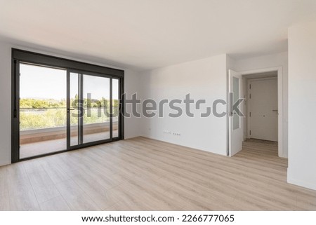 Spacious large room with wooden parquet structure and panoramic window overlooking beautiful landscape among complex of new buildings and balcony with elegant glass border. Mortgage and moving concept Royalty-Free Stock Photo #2266777065