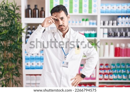 Handsome hispanic man working at pharmacy drugstore worried and stressed about a problem with hand on forehead, nervous and anxious for crisis  Royalty-Free Stock Photo #2266794575