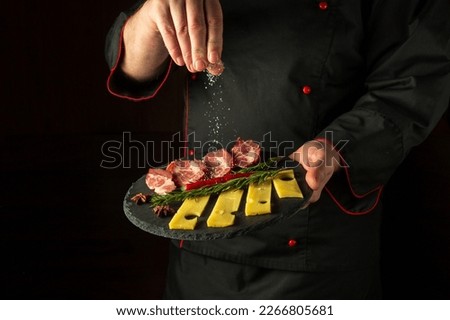 The chef sprinkles salt on a sliced steak with beef and cheese in a plate. The concept of serving dishes to order by the waiter or presentation.