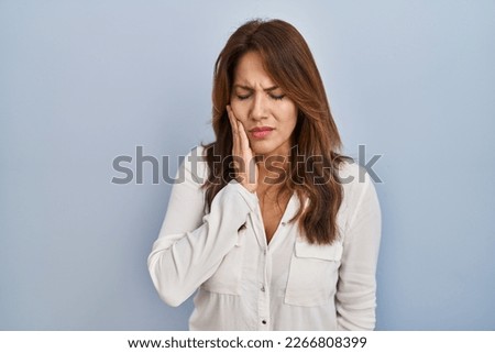 Hispanic woman standing over isolated background touching mouth with hand with painful expression because of toothache or dental illness on teeth. dentist 
