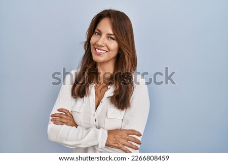 Hispanic woman standing over isolated background happy face smiling with crossed arms looking at the camera. positive person.  Royalty-Free Stock Photo #2266808459