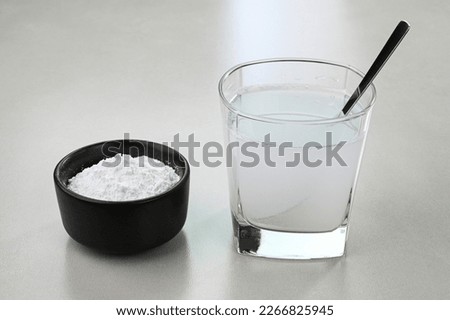 Baking powder water. Mixing baking powder and water in a glass cup.