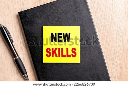 NEW SKILLS text on sticky on black notebook with pen