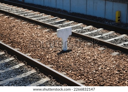 Railway sign, sign made of cement installed in the middle of two train lines, without inscriptions