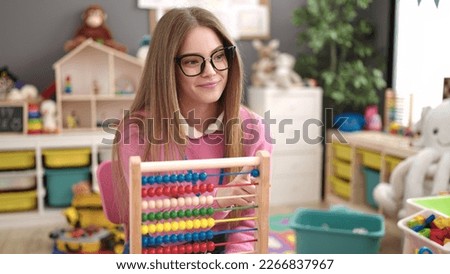 Young blonde woman preschool teacher teaching maths with abacus at kindergarten