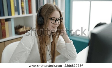 Young blonde woman student using computer studying at university classroom