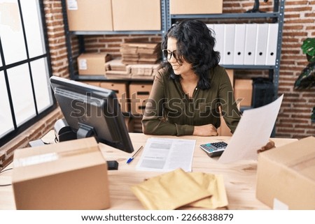 Young latin woman ecommerce business worker reading document at office Royalty-Free Stock Photo #2266838879