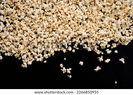 Scattered crispy popcorn on a black isolated background. View from above. The concept of a party and a movie. Copy Space.