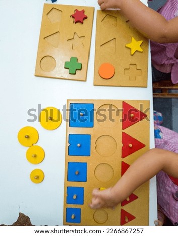 Little girls playing with colorful wooden toys learning shapes and sizes at kindergarten.