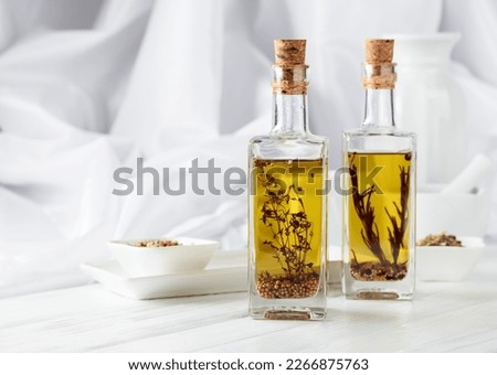 Bottles of olive oil with spices on a white wooden table. Copy space.