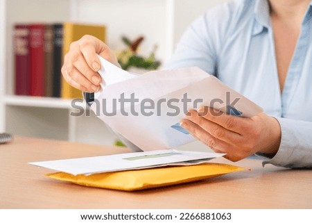 Close up of woman hands putting a letter inside an envelope on a desk at home or office Royalty-Free Stock Photo #2266881063
