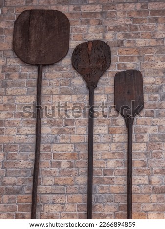 Vintage wood bread shovel. Picture of old bakery shovel. Old bakery equipment on a brick background.