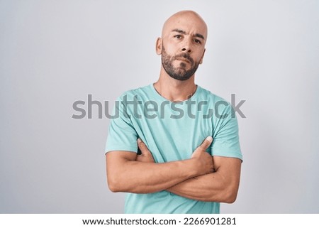 Middle age bald man standing over white background skeptic and nervous, disapproving expression on face with crossed arms. negative person. 